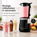 Zwarte en zilveren blender met roze milkshake in de kan, met drie glazen milkshakes ernaast.