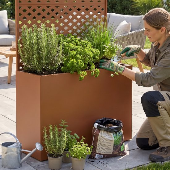 Vrouw plant kruiden in een bruine plantenbak met raster.