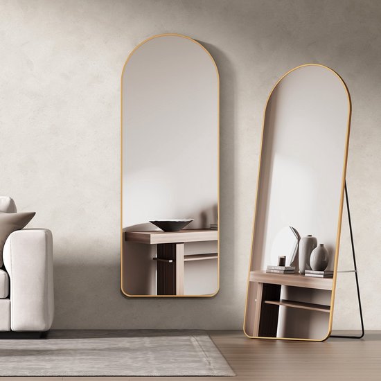 Miroir doré arqué à côté d'un canapé beige. Un second miroir est adossé au mur.