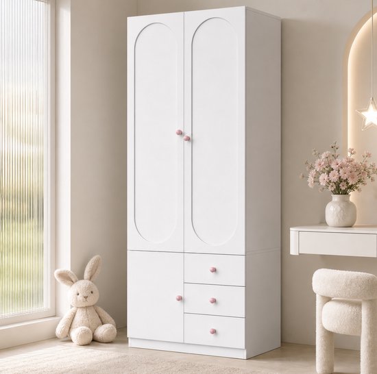 Witte kinderkledingkast met ovale deuren, roze knopjes en drie lades. Een stoffen konijn zit ernaast.