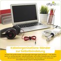 Een bureau met een laptop, koptelefoon en diverse kabels, netjes opgerold met zwarte en rode kabelbinders.