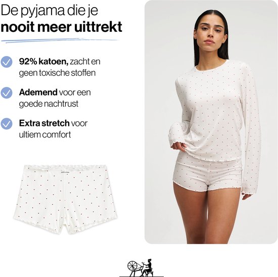 Model met witte pyjamaset met kleine rode hartjes, met lange mouwen en korte broek.