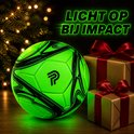 Groene voetbal met zwarte patronen, licht op en staat naast kerstcadeaus.