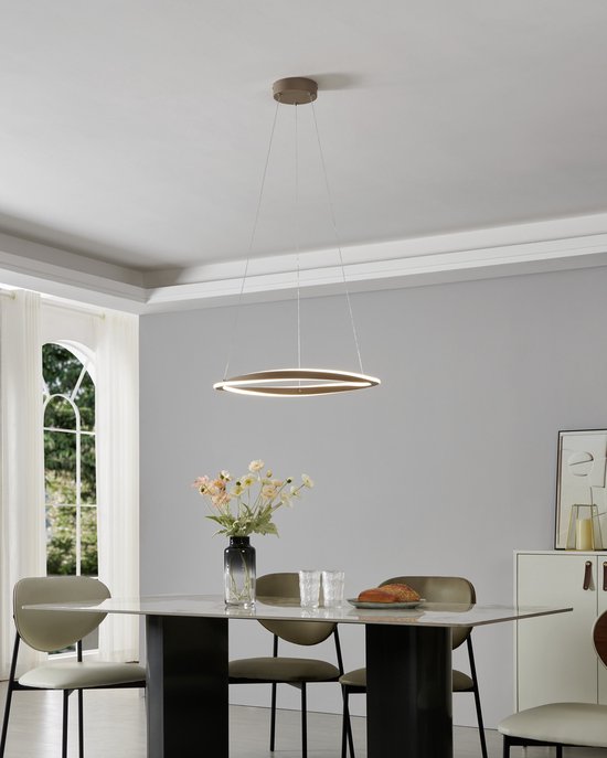 Zandkleurige ringvormige hanglamp verlicht boven een eettafel met stoelen.