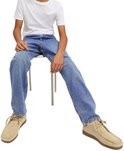 Jongen met een witte t-shirt, blauwe jeans en beige schoenen, zittend.