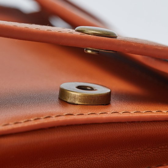 Detail van gouden knopen op een bruine tas.