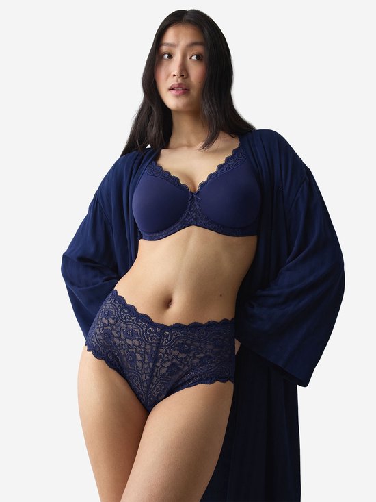 Model draagt een marineblauwe beha en slip met kant, met een bijpassende navy ochtendjas.