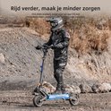 Man in zwarte motorkleding rijdt op een grijze elektrische scooter met verlichte onderkant.