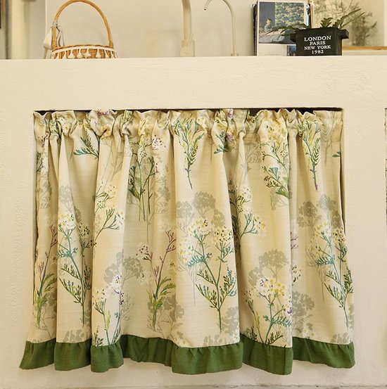 Crèmekleurige gordijntjes met bloemenprint en groene ruches, hangend in een nis.