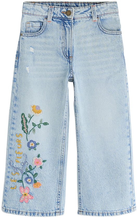 Wijde, lichtblauwe jeans met geborduurde bloemen en insecten op de linkerbroekspijp, de voorkant zichtbaar.