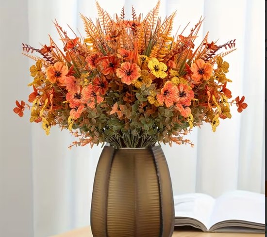 Un bouquet d'automne avec des fleurs orange et jaunes, des fougères et de l'eucalyptus dans un vase marron.