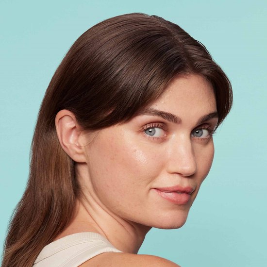 Vrouw met lang bruin haar kijkt naar rechts, met een lichte huid en blauwe ogen, tegen een blauwe achtergrond.