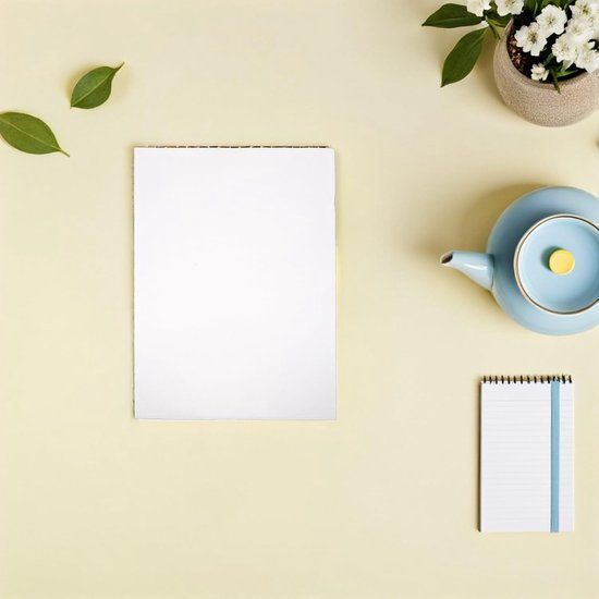 Bureau met A4 papier, pastelkleurige theepot, plant en notitieboekje.