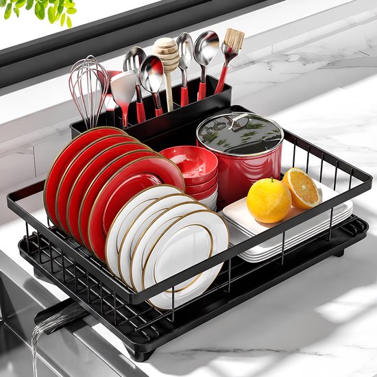 Égouttoir noir rempli d'assiettes rouges et blanches, bols rouges, casserole rouge, citrons et couverts dans un porte-ustensiles noir.
