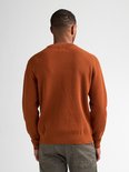 Man van Afrikaanse afkomst, rugaanzicht, draagt een oranje trui met structuur en grijze broek.