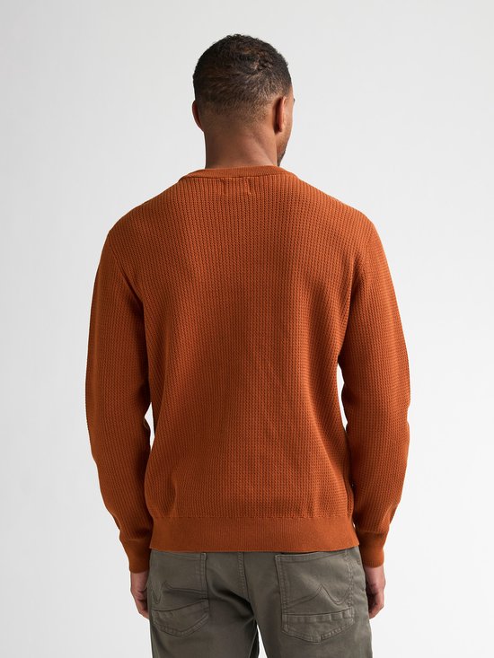 Man van Afrikaanse afkomst, rugaanzicht, draagt een oranje trui met structuur en grijze broek.