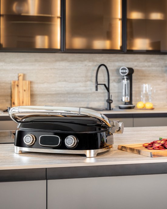 Zwarte contactgrill met chromen handgreep, ingesteld op een keukenblad.