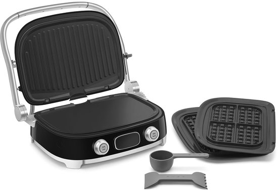 Zwarte contactgrill open, met grillplaat en extra wafelplaten, maatbeker en spatel.