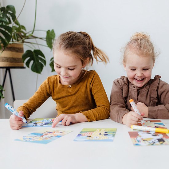 Twee lachende kinderen, een meisje en een jongen, met stempelstiften en Bluey kaarten.