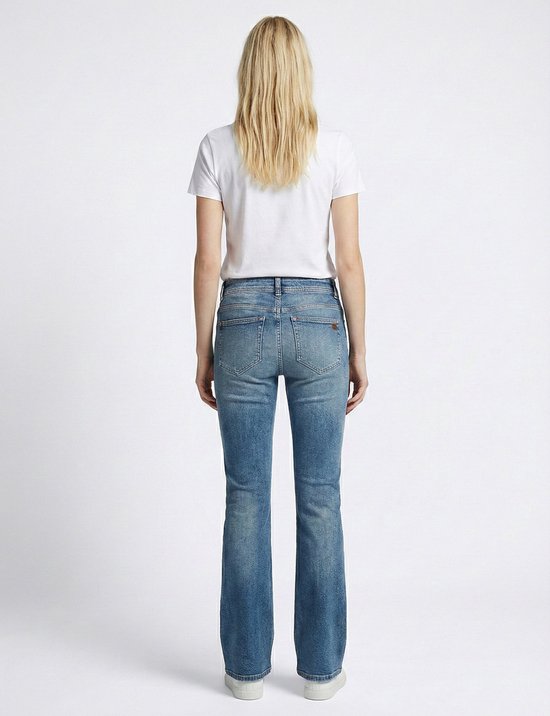 Model met witte t-shirt en jeans met uitlopende pijpen in lichtblauwe wassing, van achteren gezien.