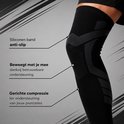Close-up van een zwarte compressie knie sleeve met grijs patroon, met tekst over anti-slip, beweging en compressie.