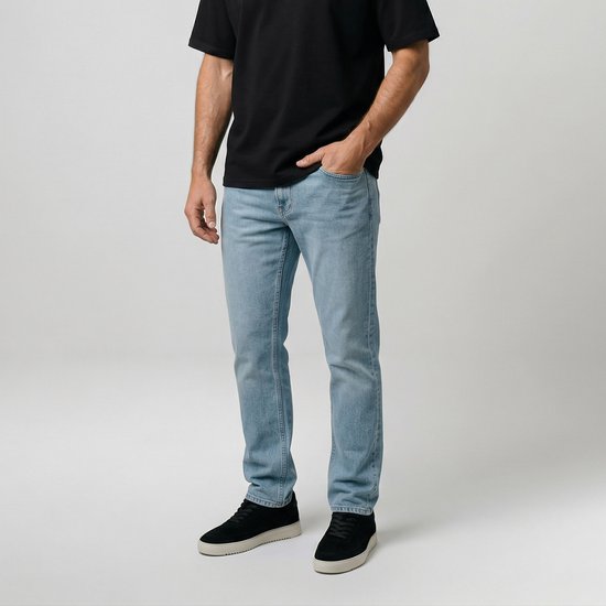 Man met korte mouwen zwart T-shirt en een lichte blauwe denim jeans, staand met hand in zak.