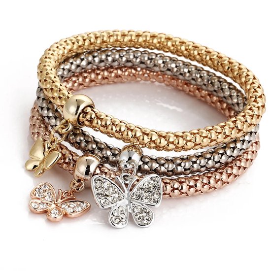 Trois bracelets extensibles dorés, argentés et couleur or rose avec des breloques papillon. Un papillon est serti de strass.
