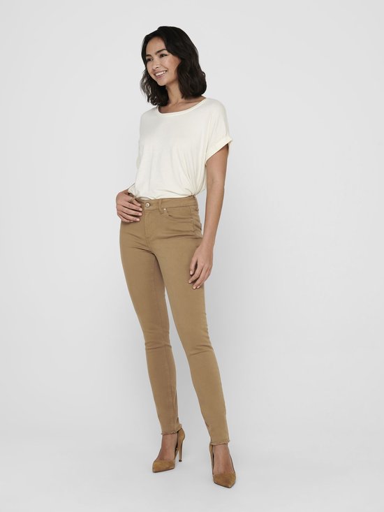 Model dat lacht in een crèmekleurig T-shirt met opgerolde mouwen en een ronde hals. Draagt een beige skinny broek.