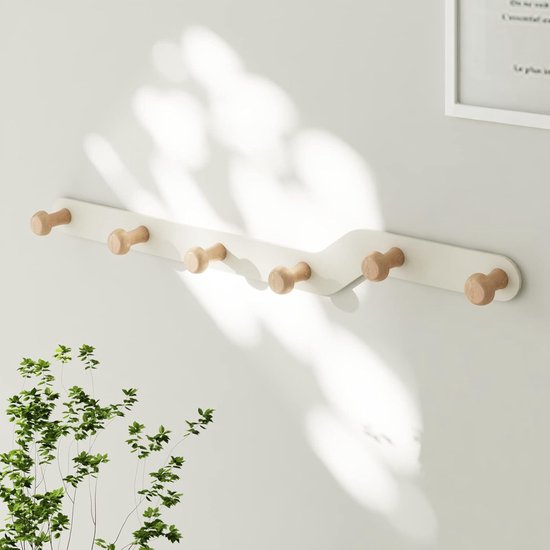 Een witte kapstok met zeven houten knoppen, gemonteerd op een muur.