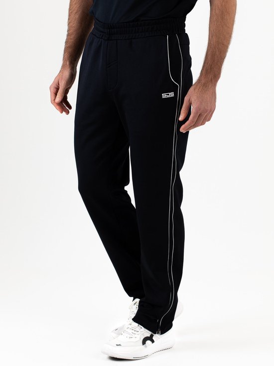 Man in donkere sportbroek met witte bies en SJS logo, gedragen met witte sneakers.