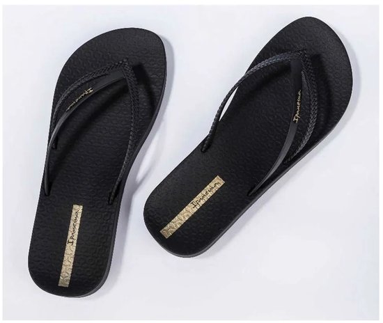 Zwarte Ipanema slippers, schuin van voren gezien, met gevlochten bandjes en gouden logo.