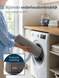 Grijze handdoek wordt in een wasmachine gestopt, diep donkergrijs bankkussen met ritssluiting.