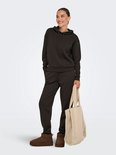 Vrouw met een donkere hoodie en joggingbroek, draagt een beige teddy shopper.