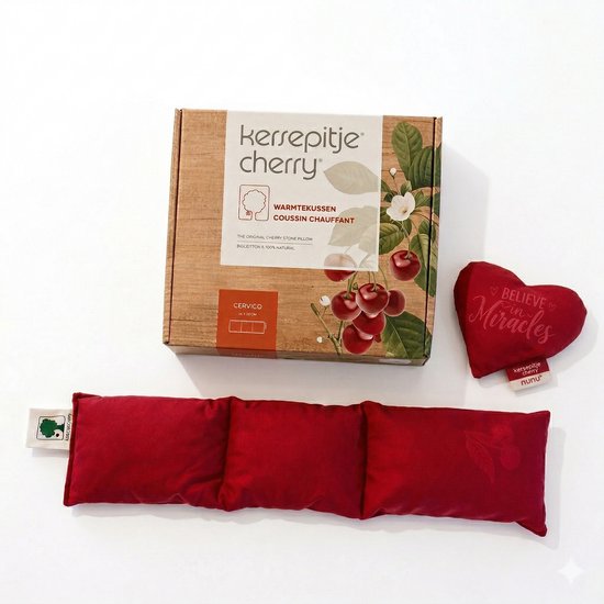 Een rood, langwerpig kersenpitkussen met drie compartimenten, een klein rood hartvormig kussen met de tekst 'Believe in Miracles' en een kartonnen verpakking met kersenafbeelding.