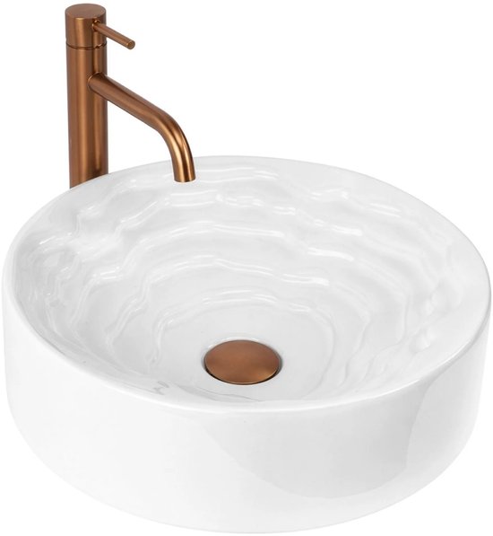 Witte wastafel met golvend patroon en bronzen afvoer, met bronzen kraan.