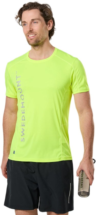 Homme marchant vers le spectateur, portant un t-shirt jaune fluo avec le texte vertical 'SWEDEMOUNT', un short noir et des baskets blanches.