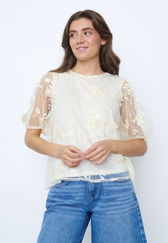 Mannequin portant une chemise couleur crème à manches courtes bouffantes et appliqués floraux.