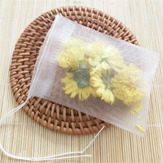 Witte theezakje gevuld met gele chrysanten, op een bruin vlechtwerk onderzetter.