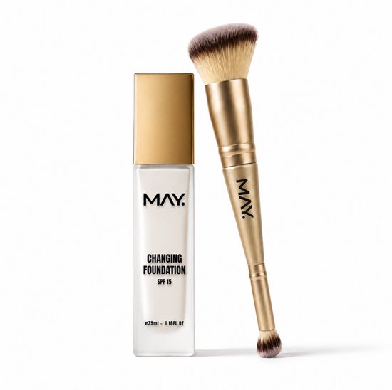 Witte MAY Changing Foundation fles met gouden dop, naast een gouden foundationkwast met gouden dop.