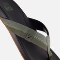 Close-up van een zwarte slipper met olijfgroene band, textuur, stiksels en Reef logo.