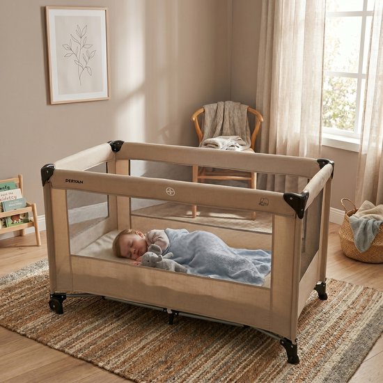 Baby slapend in beige Deryan campingbedje met gaaswanden en blauwe deken.