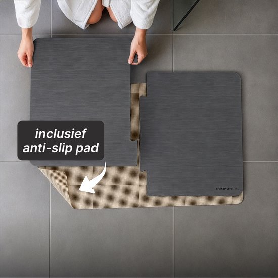 Twee donkergrijze badmat-delen die samengevoegd worden. Anti-slip pad is zichtbaar. Tekst: inclusief anti-slip pad.
