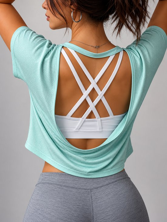 Mouwloze mintgroene sporttop met open rug en gekruiste bandjes, gedragen door een model met grijze sportbroek.