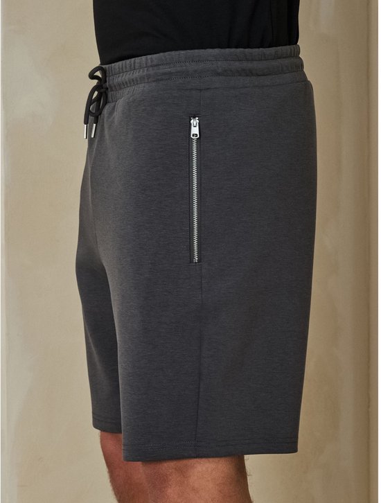 Zijaanzicht van een grijze jersey short met een opvallende ritszak.