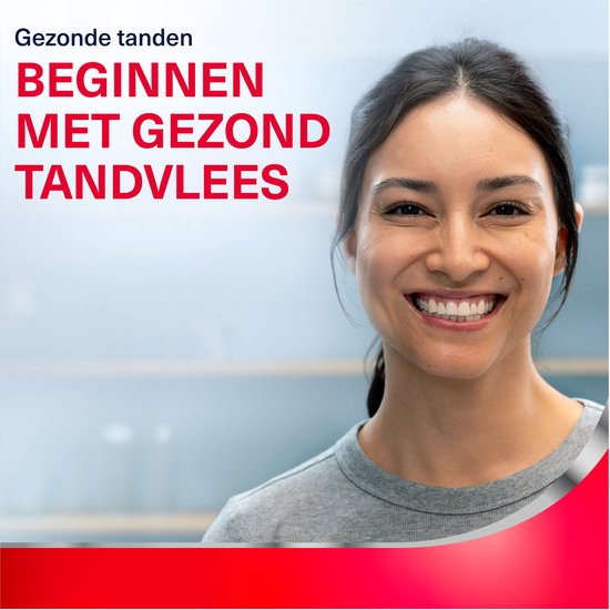 Vrouw met donker haar lacht en wijst naar haar tanden. Tekst: Gezonde tanden beginnen met gezond tandvlees.