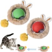 Twee pluizige, ronde speeltjes met konijnenoortjes. Eén heeft een groene bal, de ander een rode bal. Een kleine cyperkat speelt met een groen speeltje op een witte achtergrond.