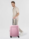 Man met een beige polo en broek, duwt een roze American Tourister koffer.