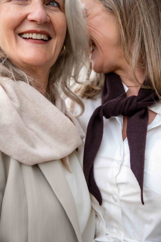 Twee vrouwen met grijze haren. Eén met een crèmekleurige sjaal, de ander met een donkerbruine gebreide sjaal om de nek.