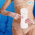 Vrouw met vitiligo houdt een TENA Discreet Extra verband omhoog.