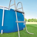 Grijze ladder bij een ronde blauwe zwembad.